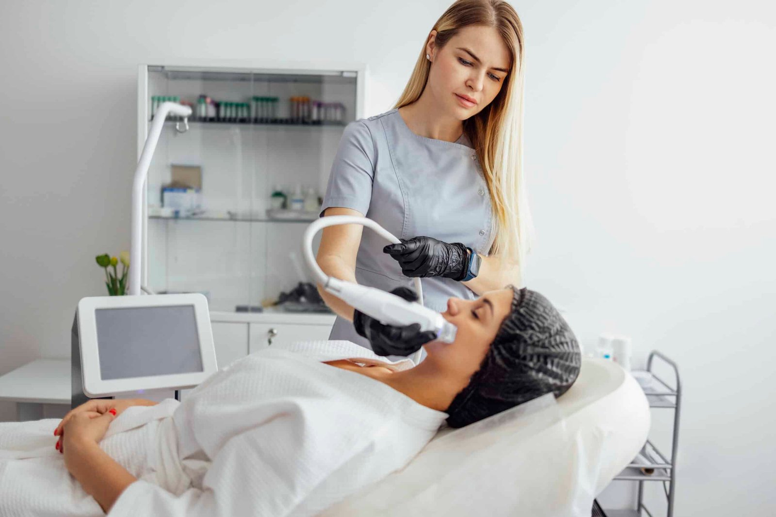 Microneedle RF lifting procedure. Hardware cosmetology. Beautician conducts a facial rejuvenation procedure for a brunette woman